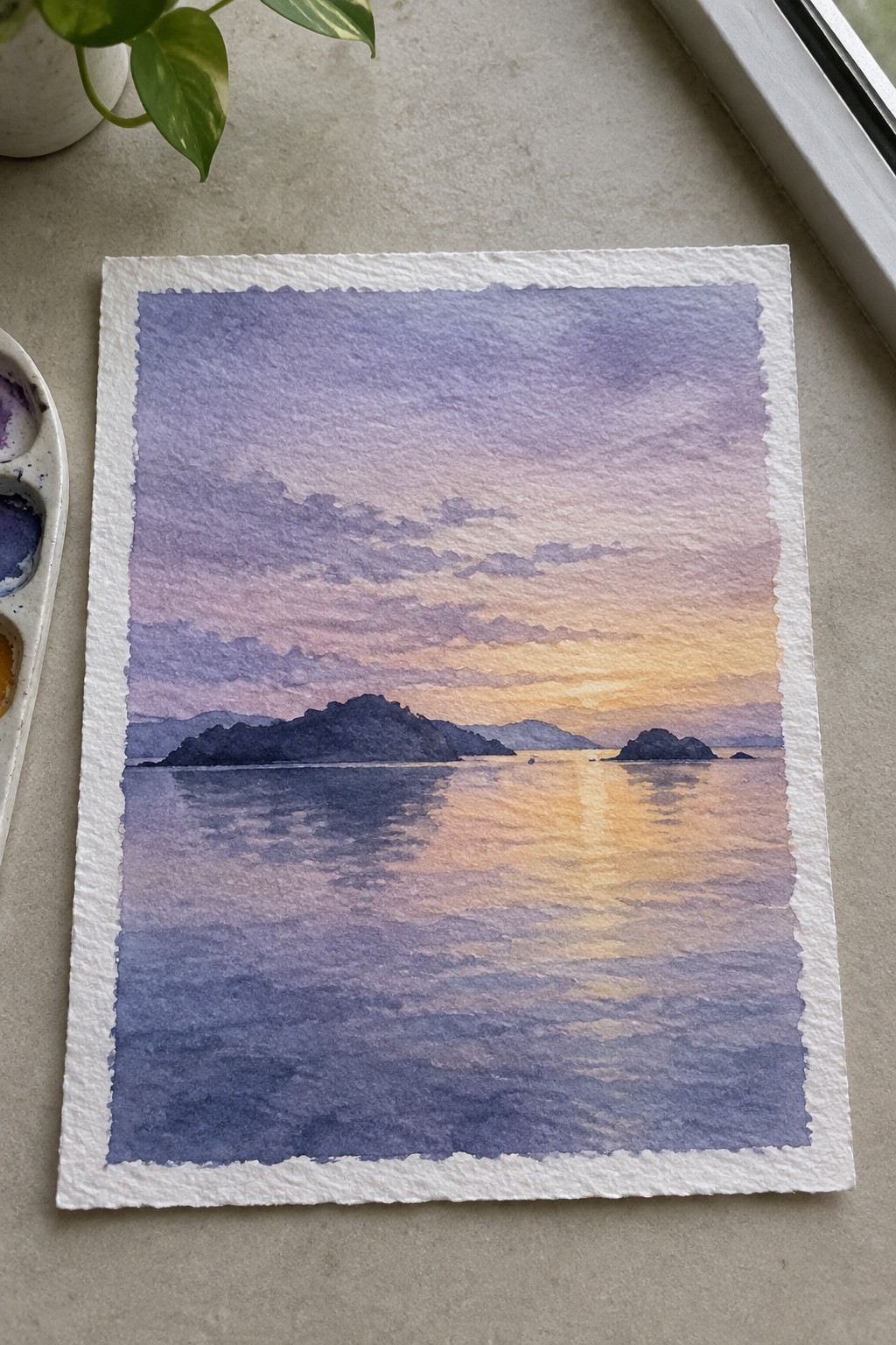 Watercolor sunset seascape with purple-orange sky, dark islands, reflections, paint palette nearby.