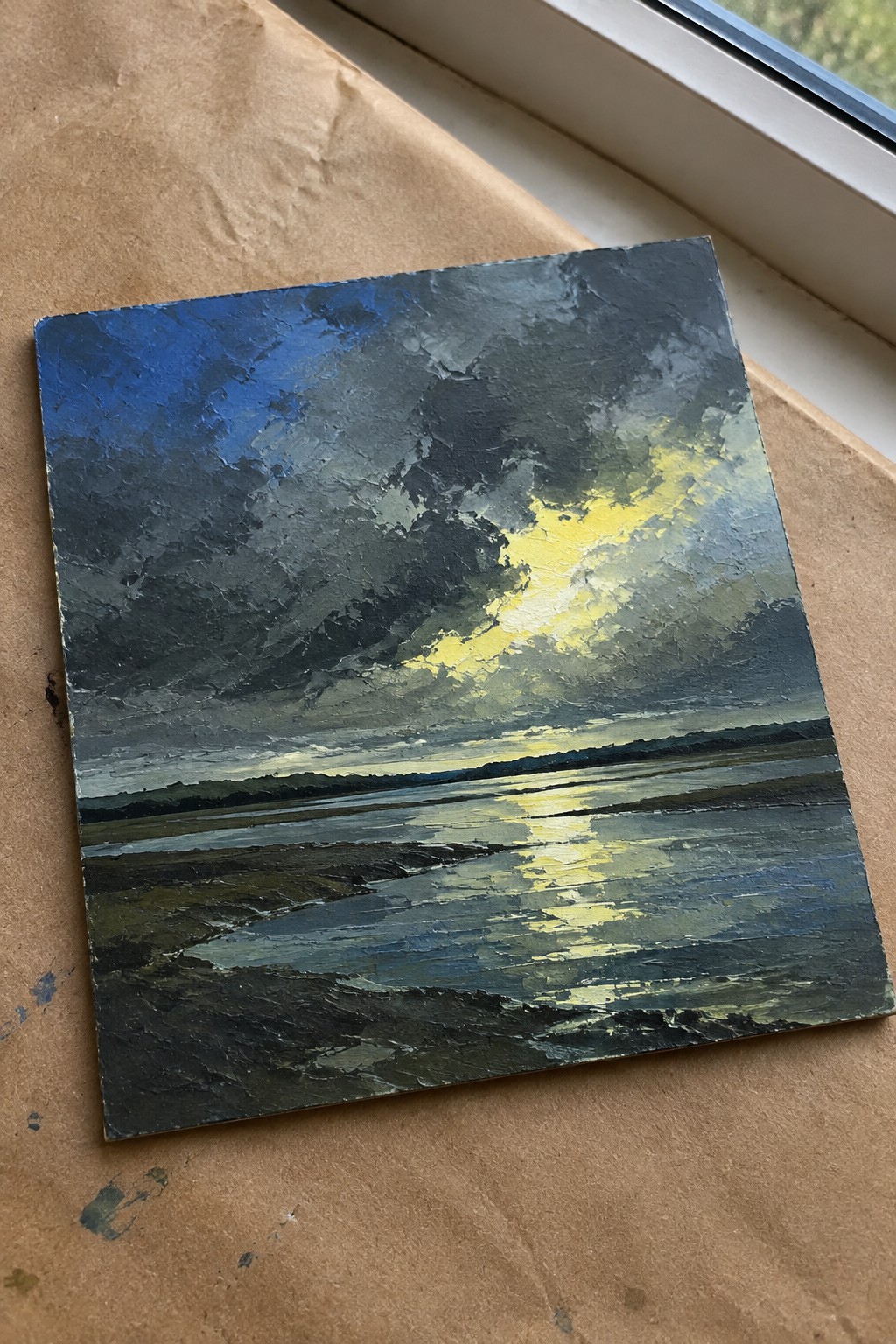 Thickly textured oil painting of stormy clouds with yellow light reflecting on water