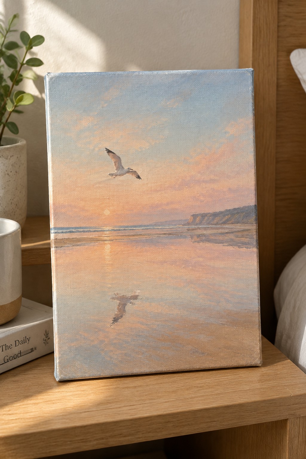 Seascape painting of seagull flying over sunset ocean with cliffs on wooden table