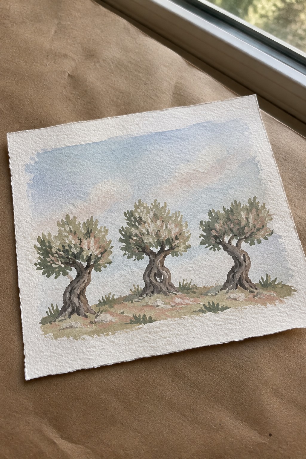 Watercolor of three gnarled trees on a hill under a cloudy blue sky