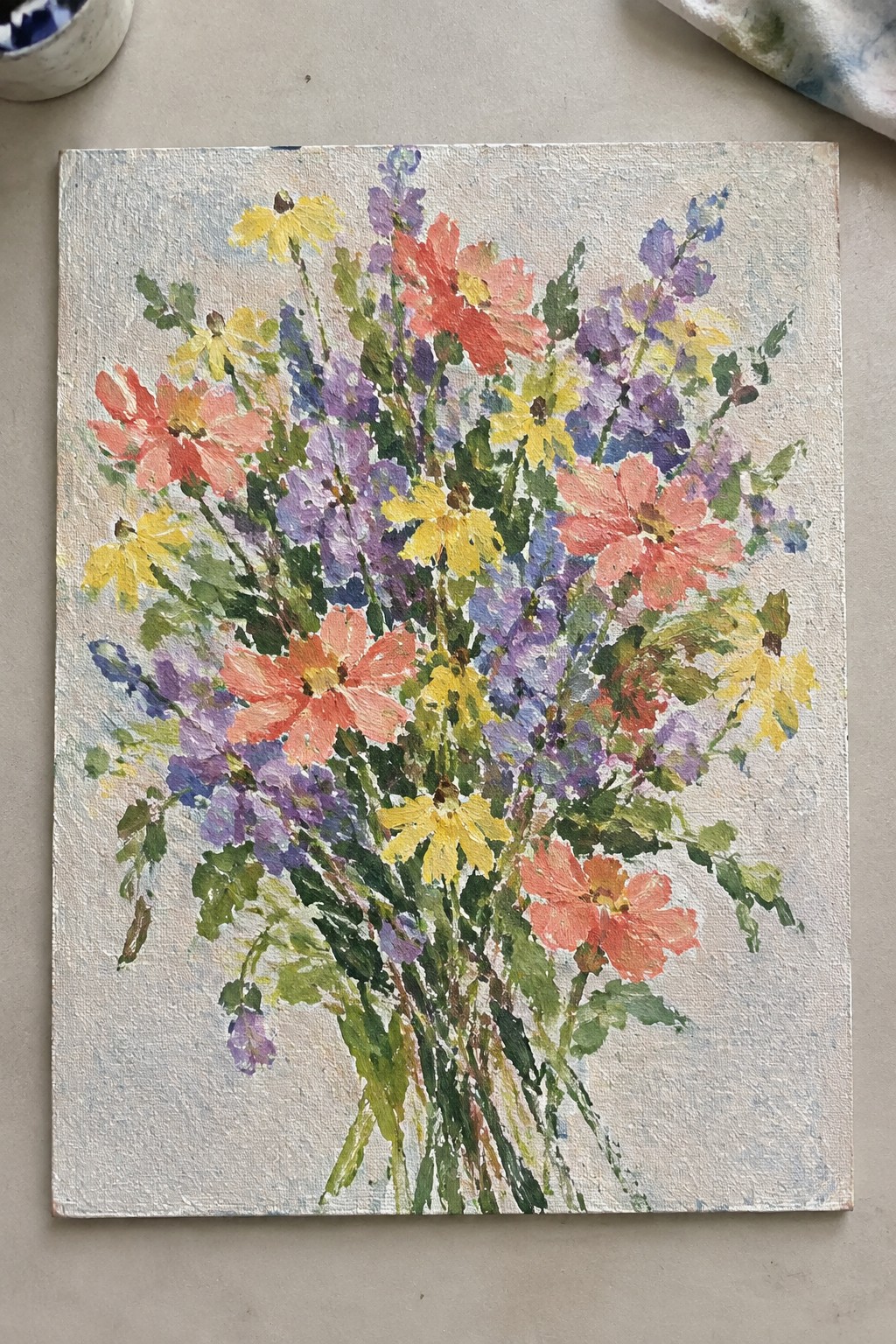 Vibrant impressionist painting of pink, yellow, and purple wildflowers with green stems on canvas