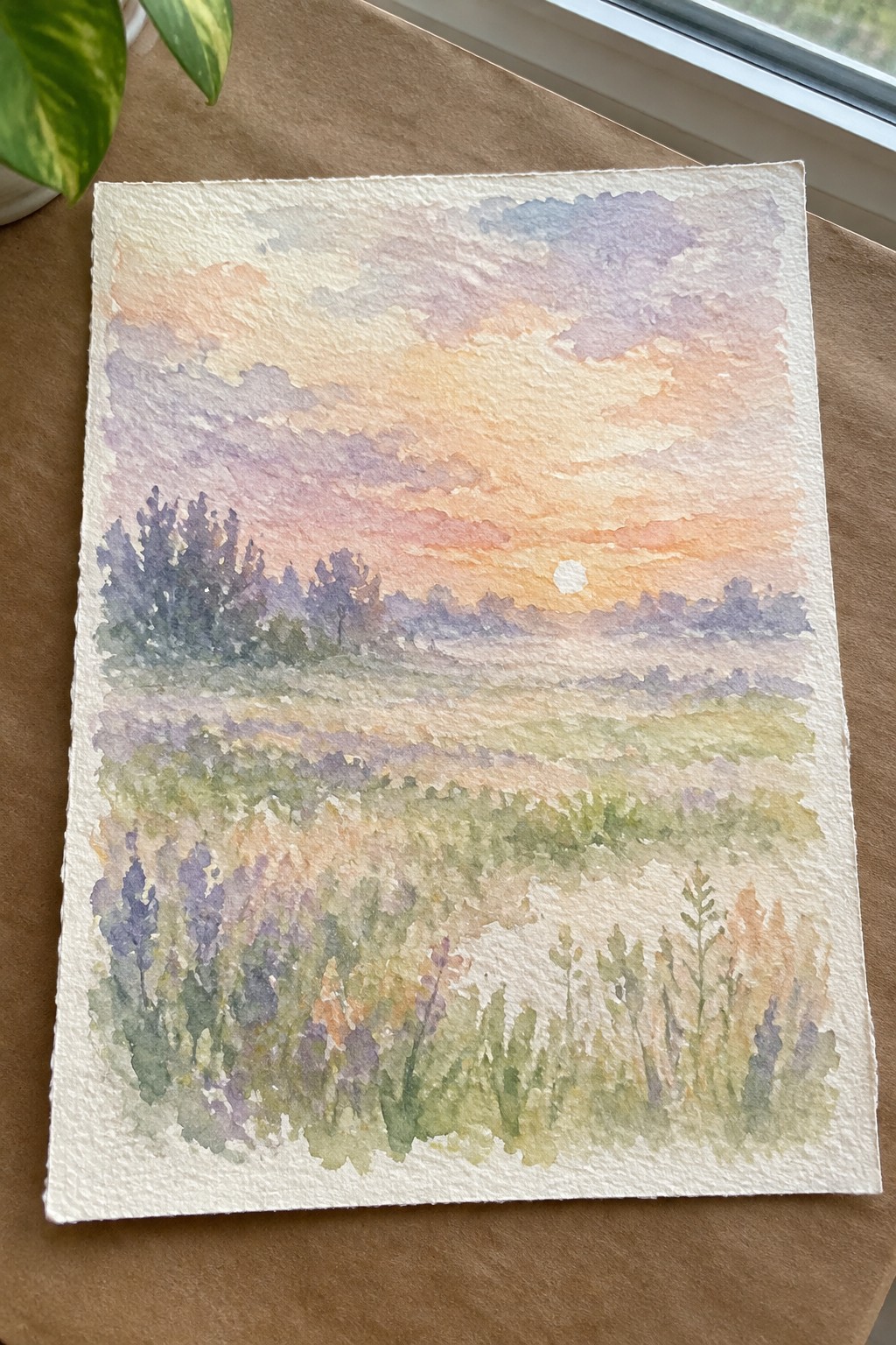 Watercolor sunset landscape with orange-pink sky, purple wildflowers, and silhouetted trees.