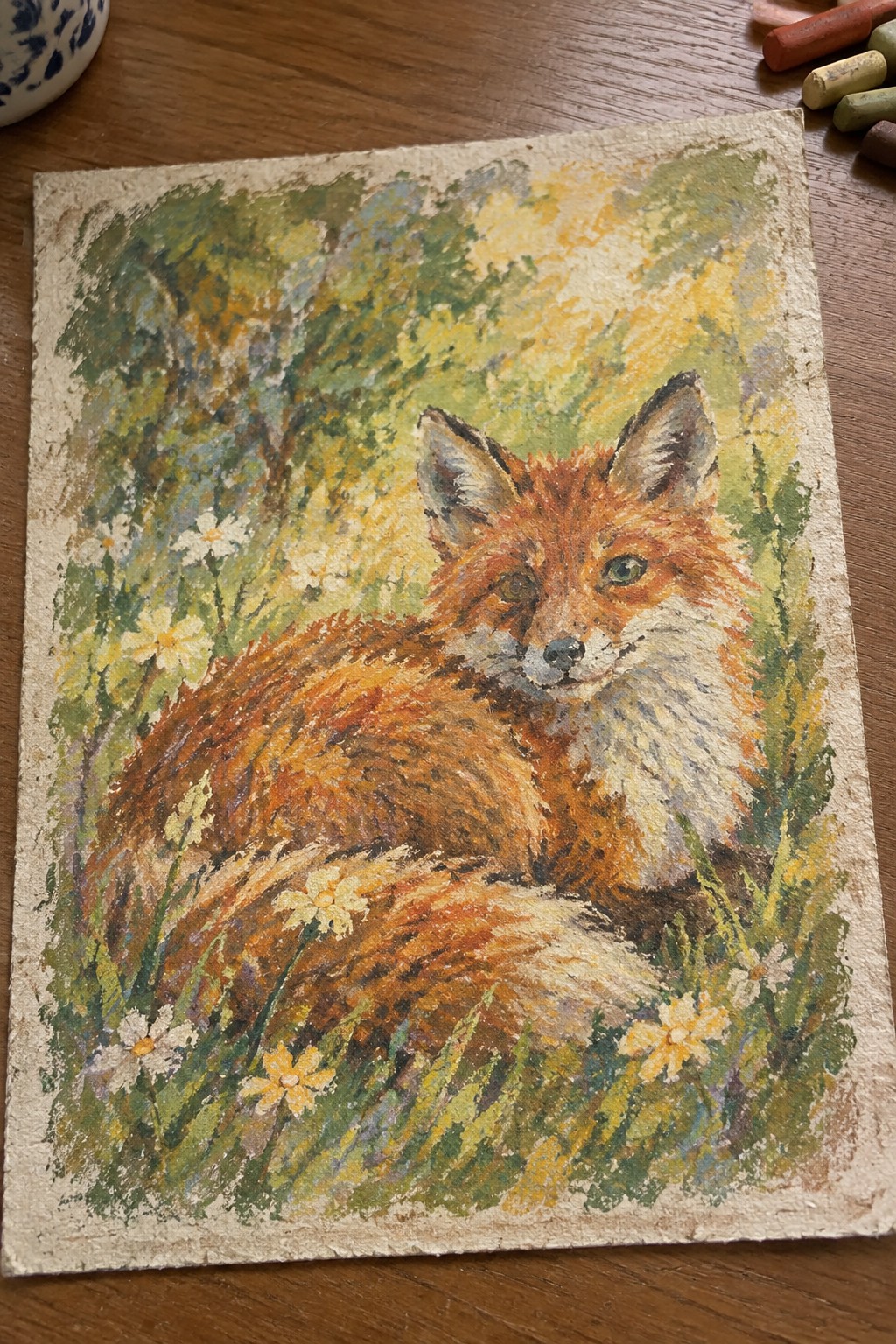 Orange fox resting among yellow flowers in sunlit green woodland pastel drawing