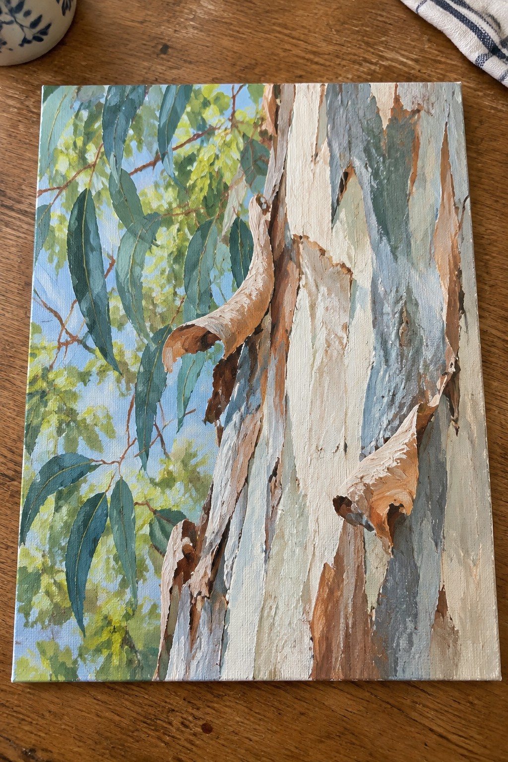 Painting of tree trunk with peeling white gray brown bark and green leaves