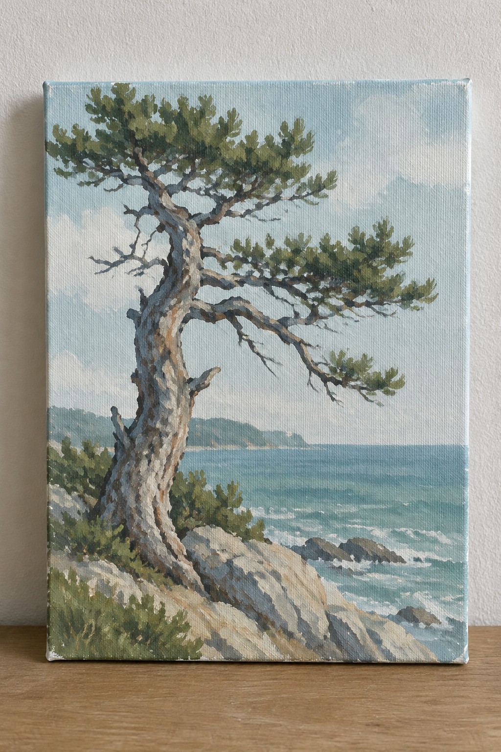 Gnarled pine tree on rocky cliff overlooking blue ocean with white waves