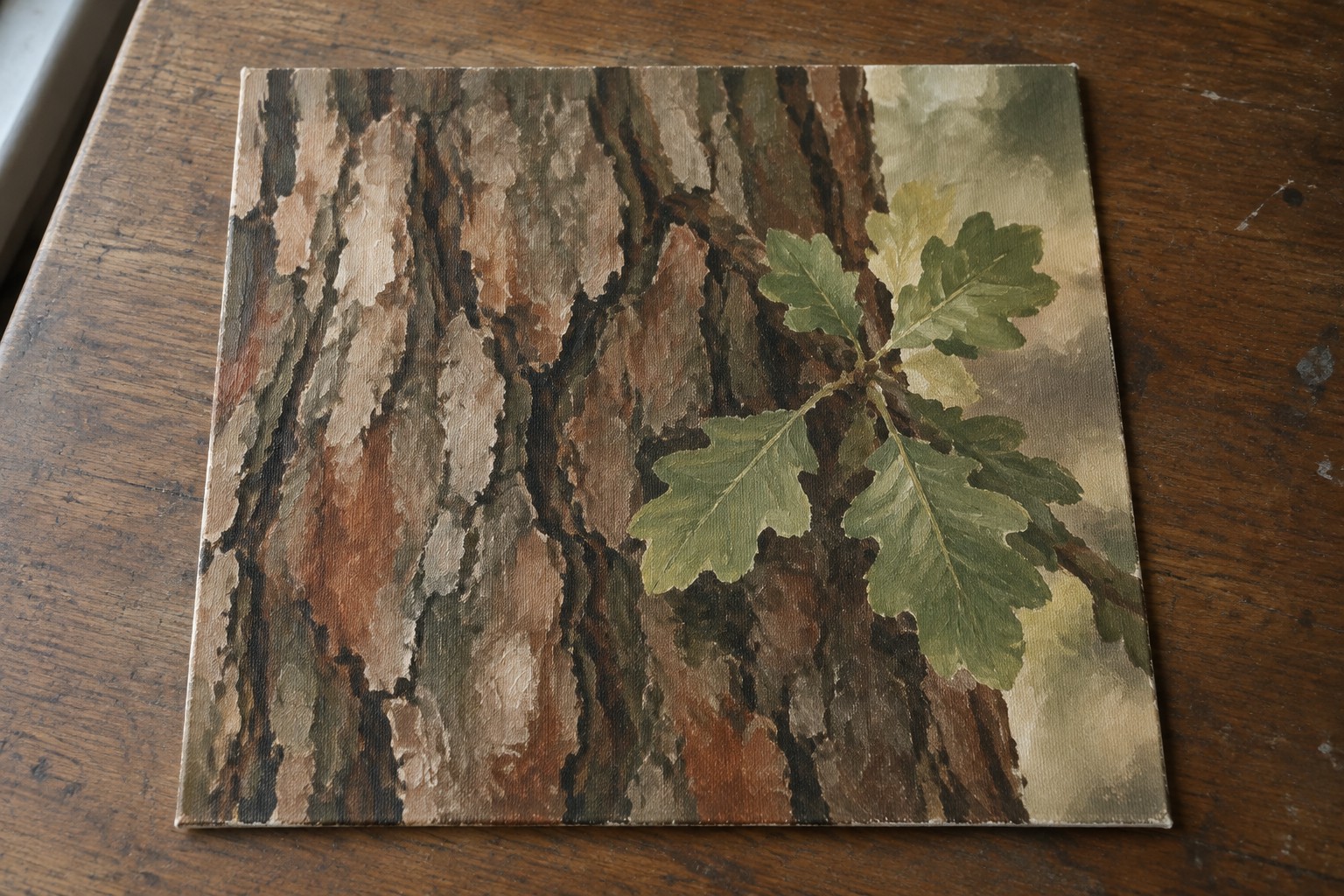 Painting of textured brown tree bark with green leaves on wooden table
