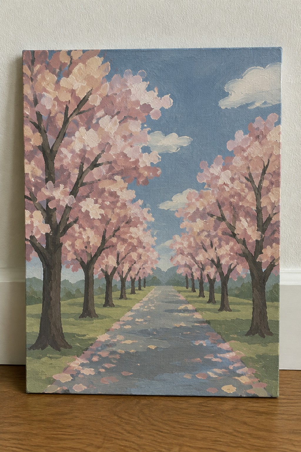 Painting of cherry blossom trees lining a petal-covered path under blue sky.