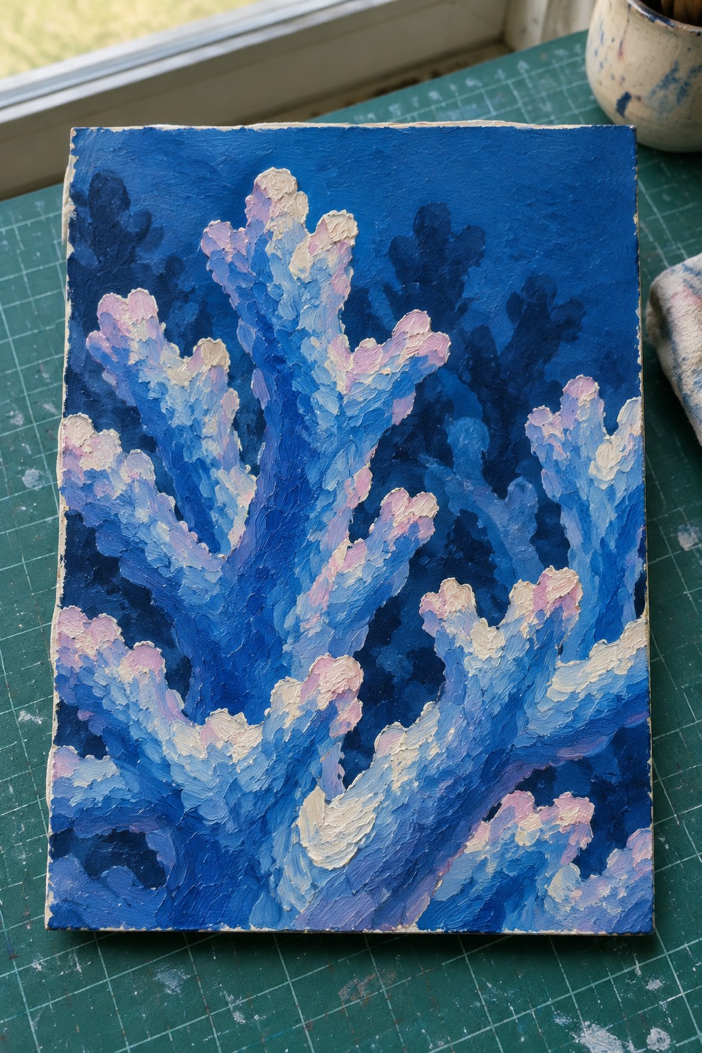 Thickly textured painting of blue coral branches with pink and white accents