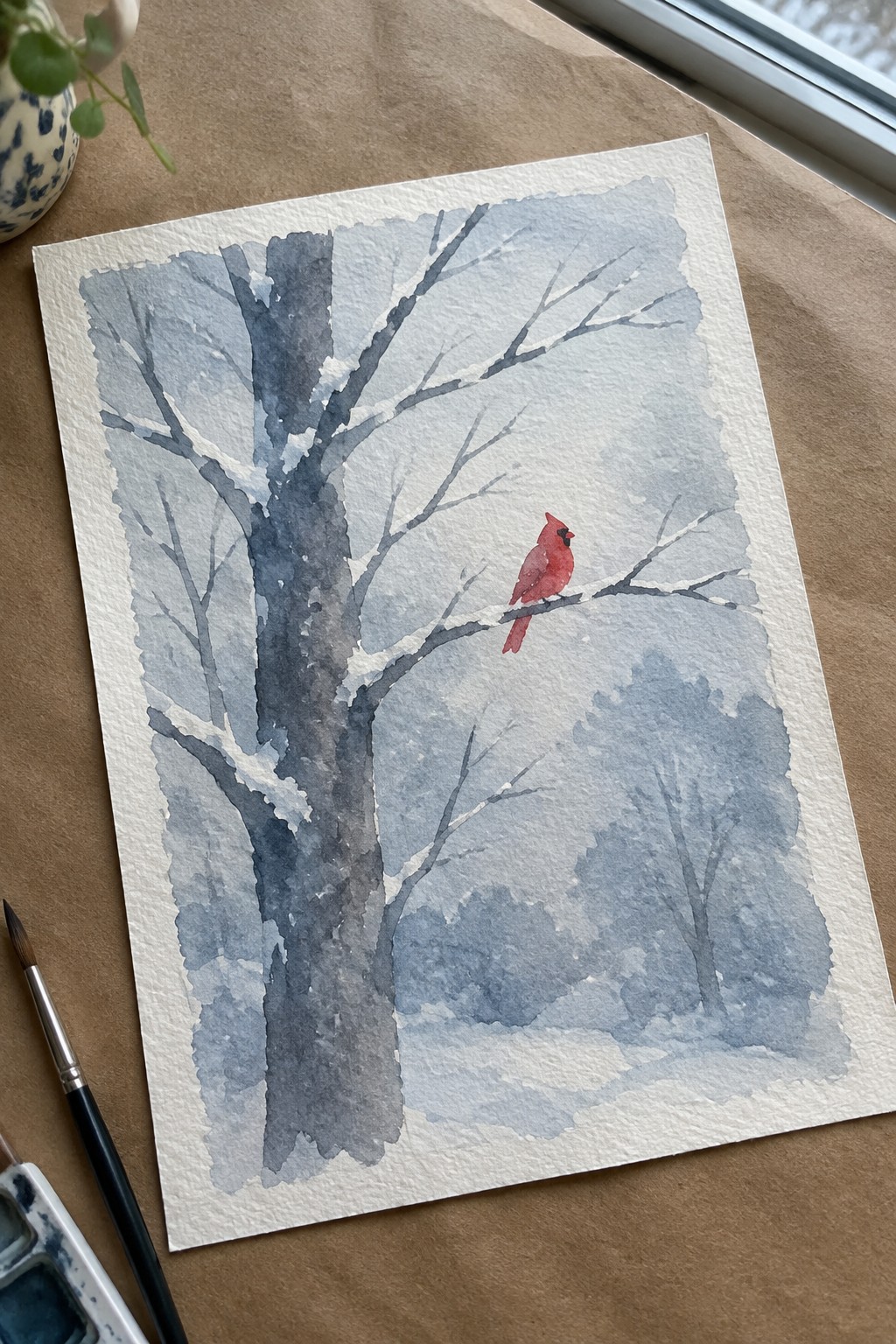 Watercolor of red cardinal perched on snow-covered tree branch in misty winter scene