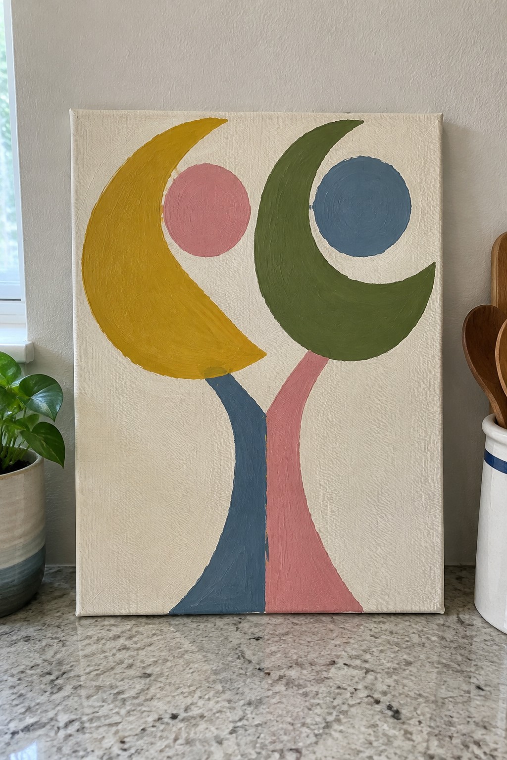 Abstract painting with yellow and green crescents, pink and blue circles on beige canvas