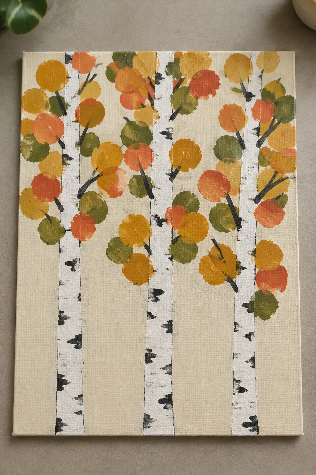 Birch tree trunks with black marks and colorful orange yellow green foliage circles