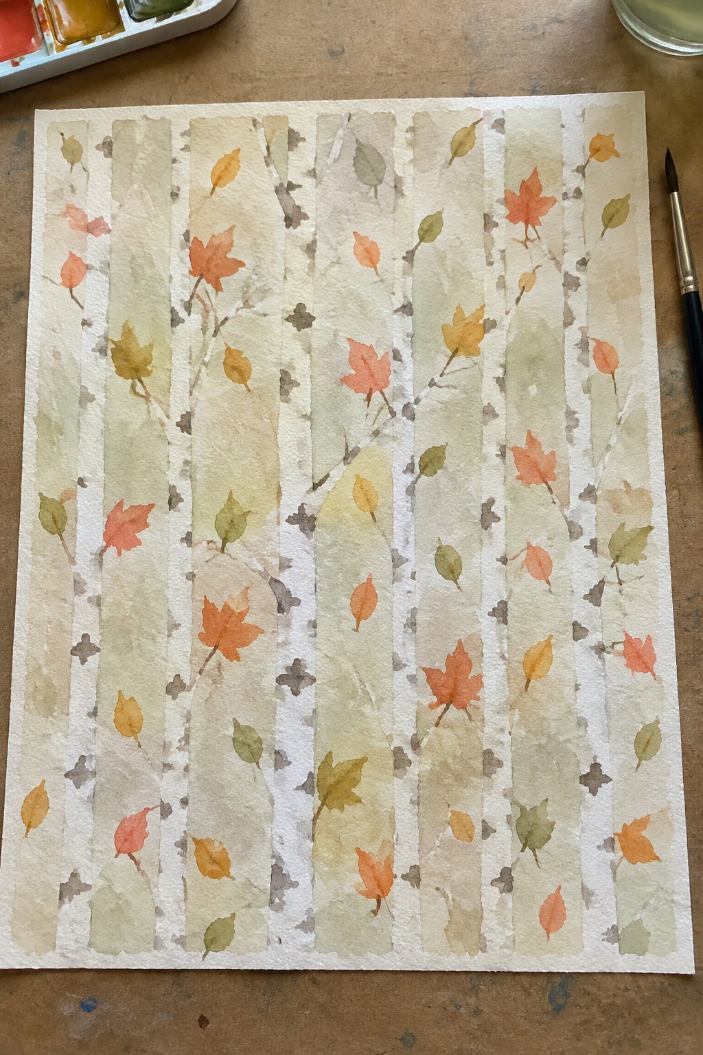 Watercolor of white birch trunks with scattered orange, yellow and red autumn leaves.