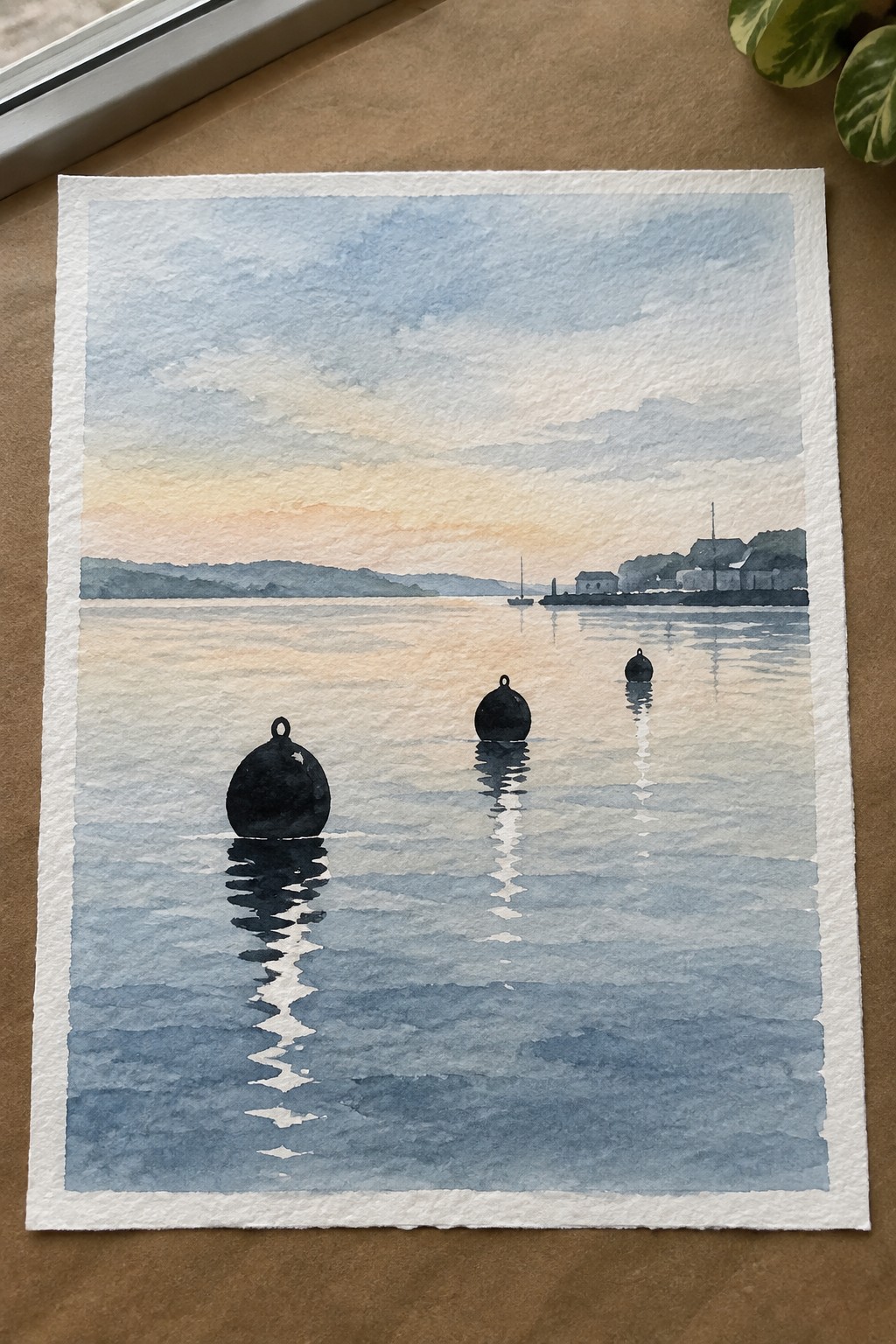 Three dark buoys float in calm water with white reflections below them, a faint shoreline visible in the distance under a soft sky.
