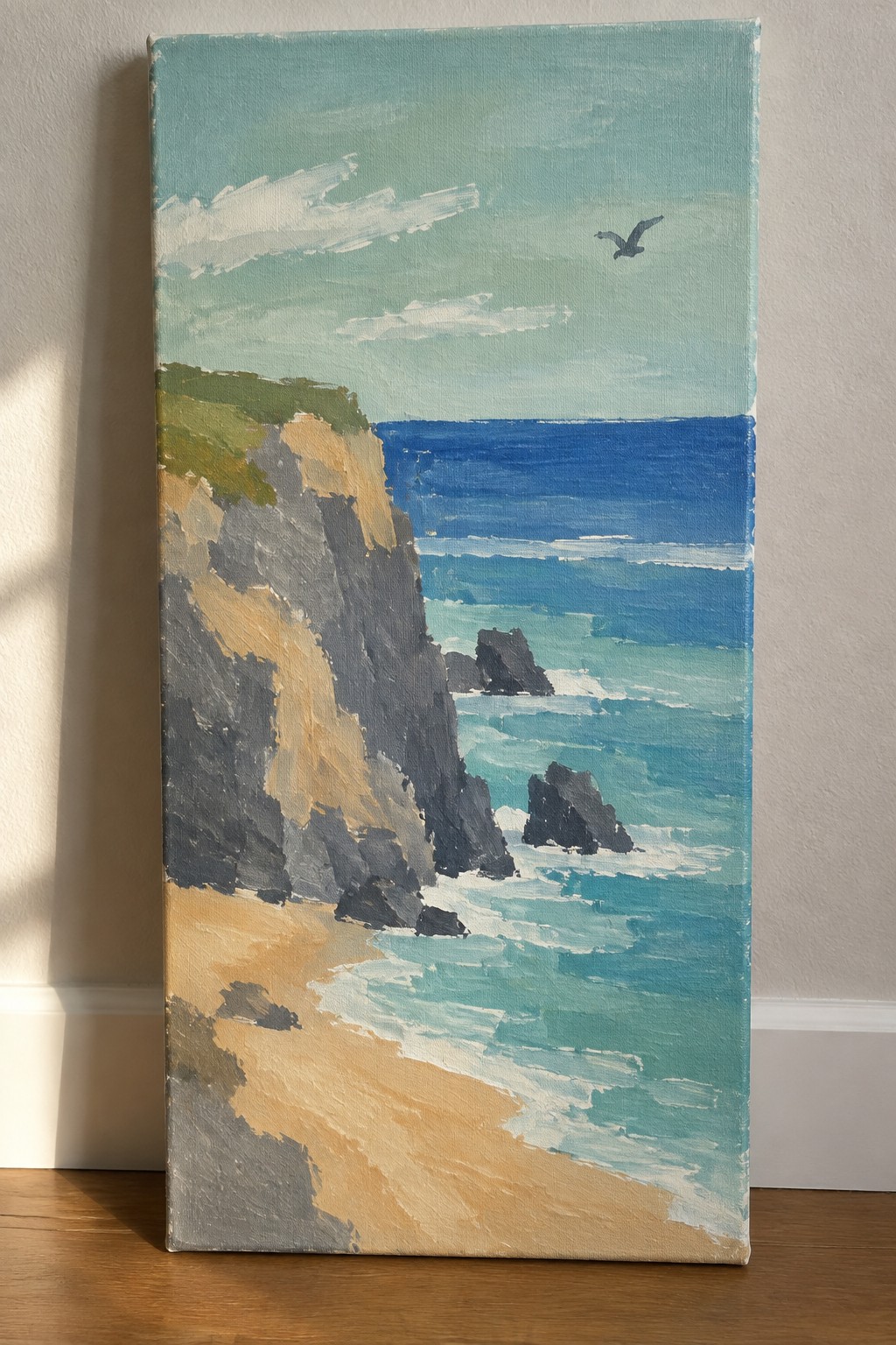Acrylic painting of rocky cliffs, sandy beach, blue ocean, and flying bird.