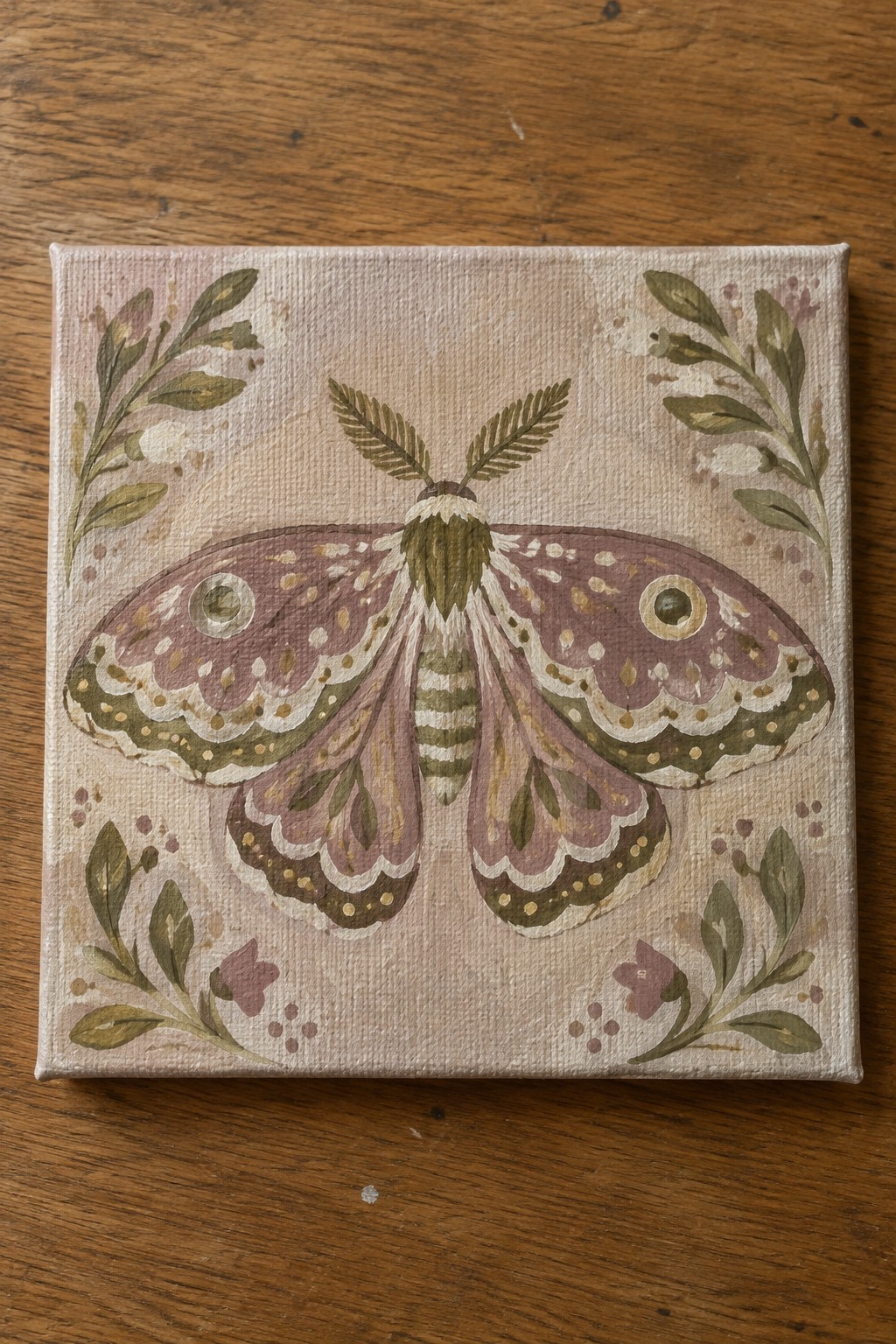 Watercolor moth with purple wings, eye spots, and green foliage on canvas