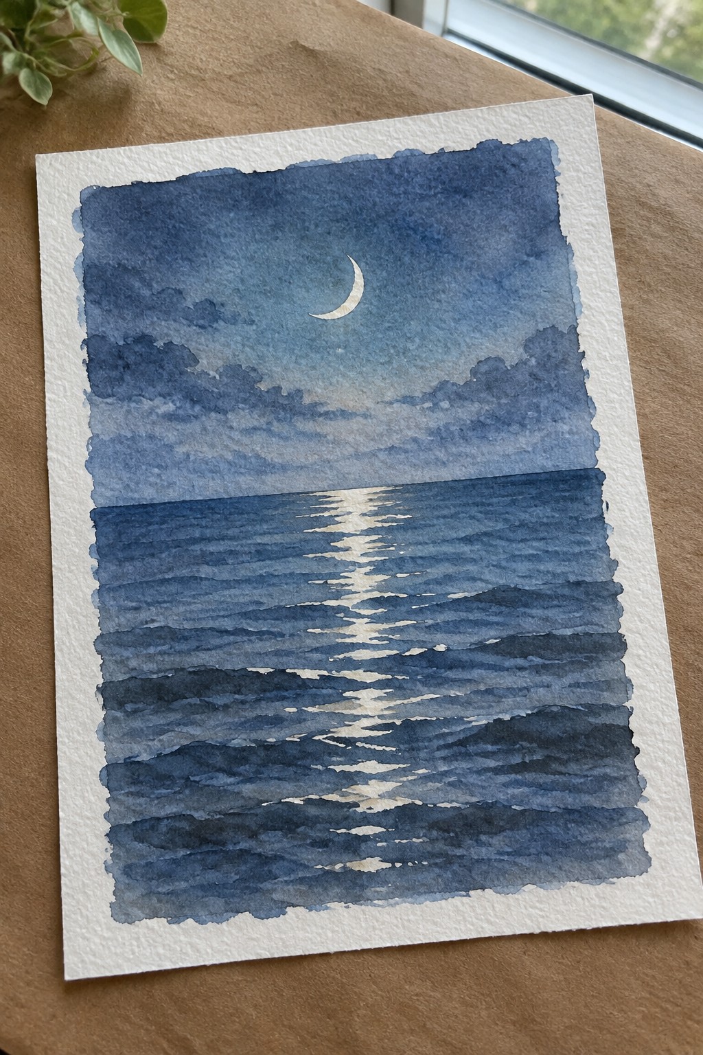 Watercolor painting of crescent moon over dark blue ocean with moonlight reflecting on waves.
