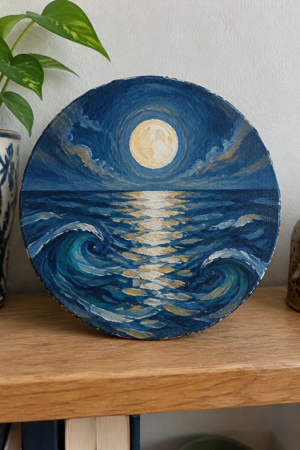 Circular painting of full moon reflecting on blue ocean waves with gold highlights