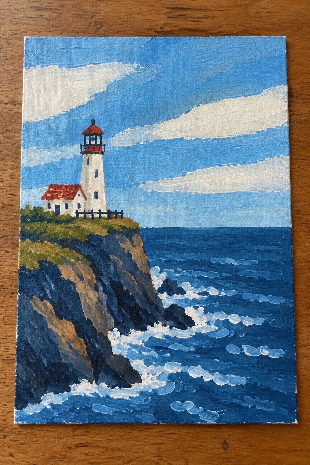 White lighthouse with red roof on cliff above blue ocean waves under cloudy sky