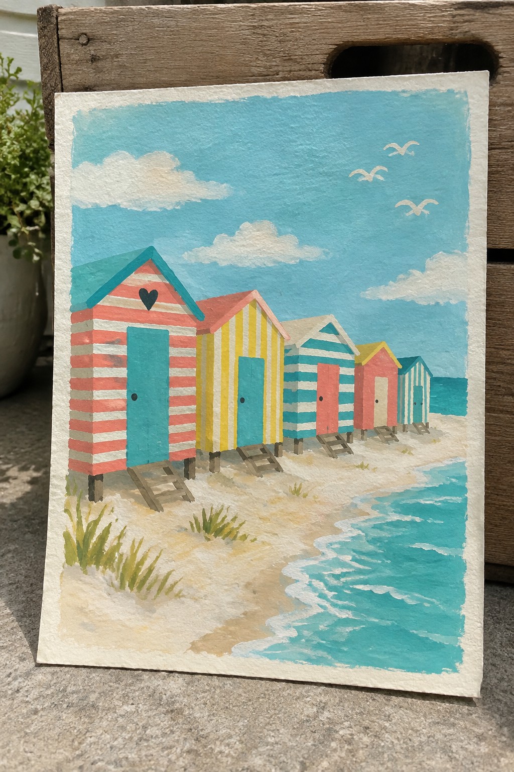 A painting of several colorful striped beach huts lined up on sand next to blue water under a sky with clouds and birds.