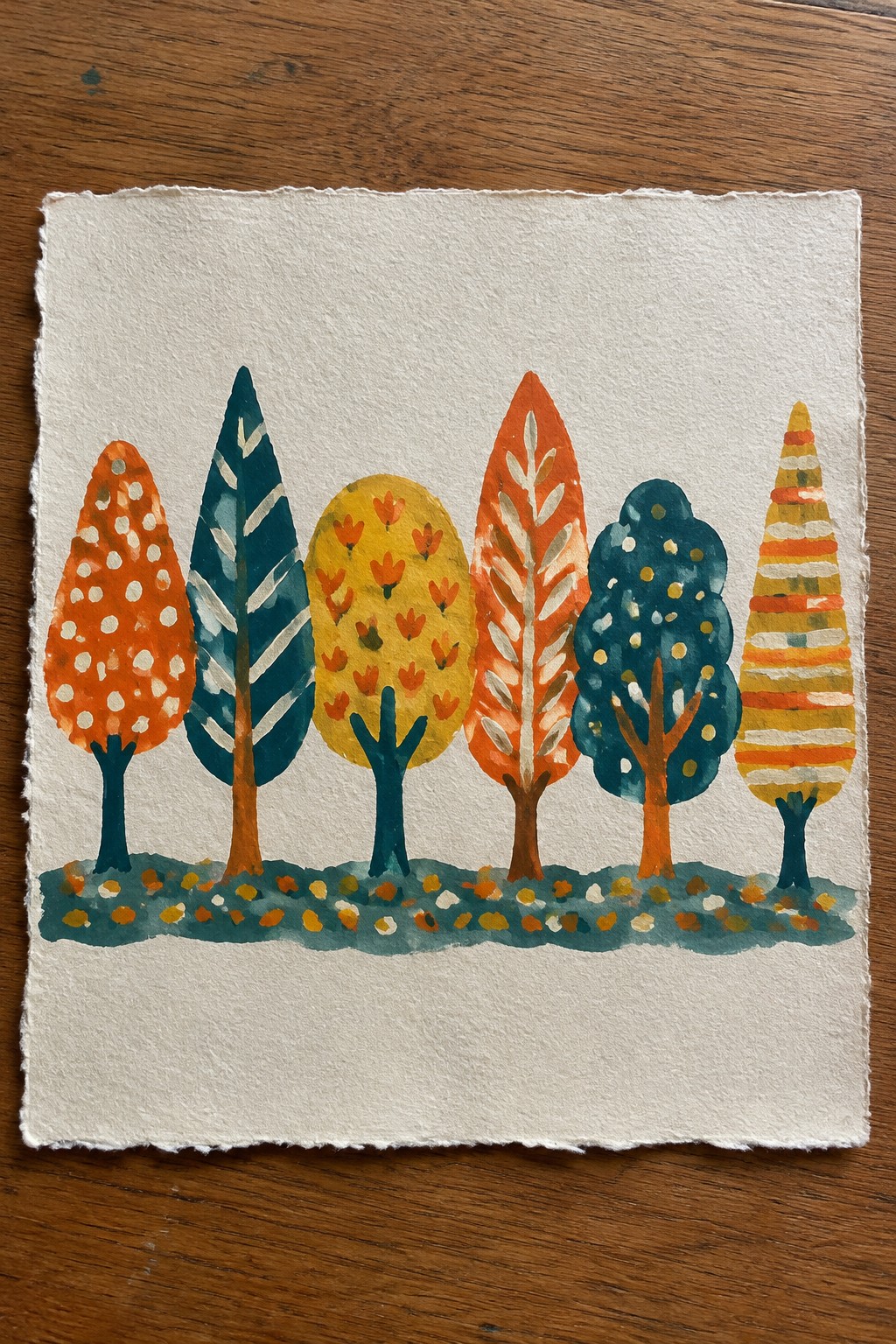 Watercolor painting of six patterned autumn trees on white paper over wood