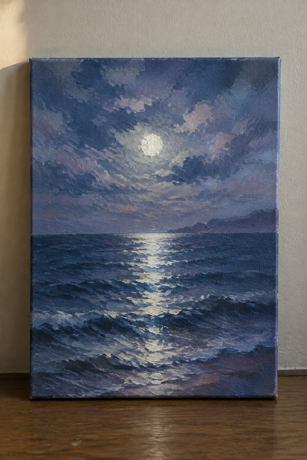 An oil painting of a full moon breaking through clouds above a dark blue ocean, with a bright white reflection stretching across the waves toward distant hills.