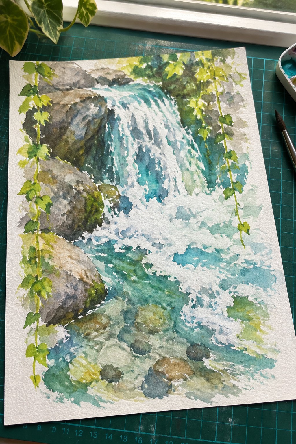 Watercolor painting of turquoise waterfall cascading over gray rocks with hanging green ivy