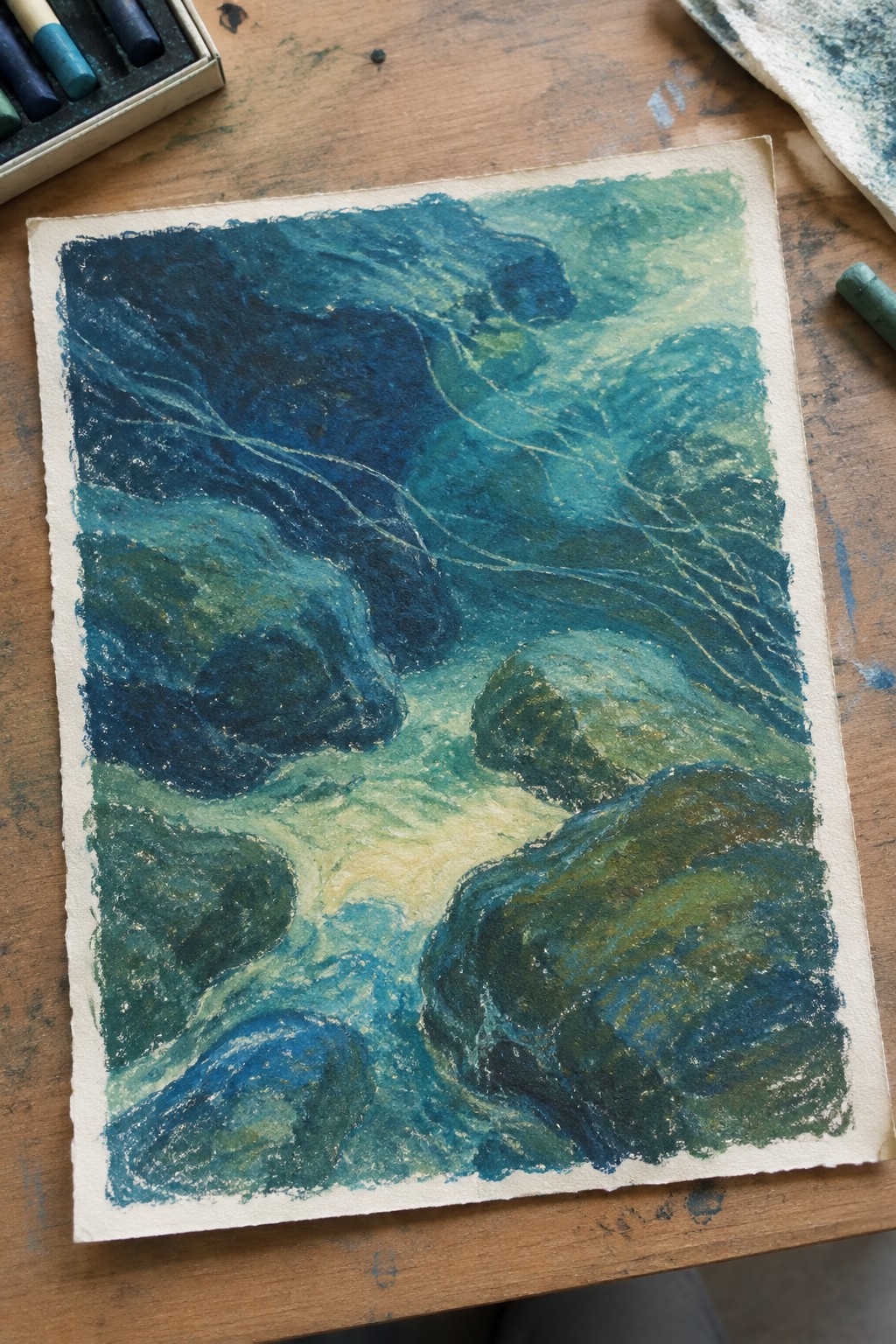 Abstract blue-green watercolor of swirling waters flowing around moss-covered rocks on wood table