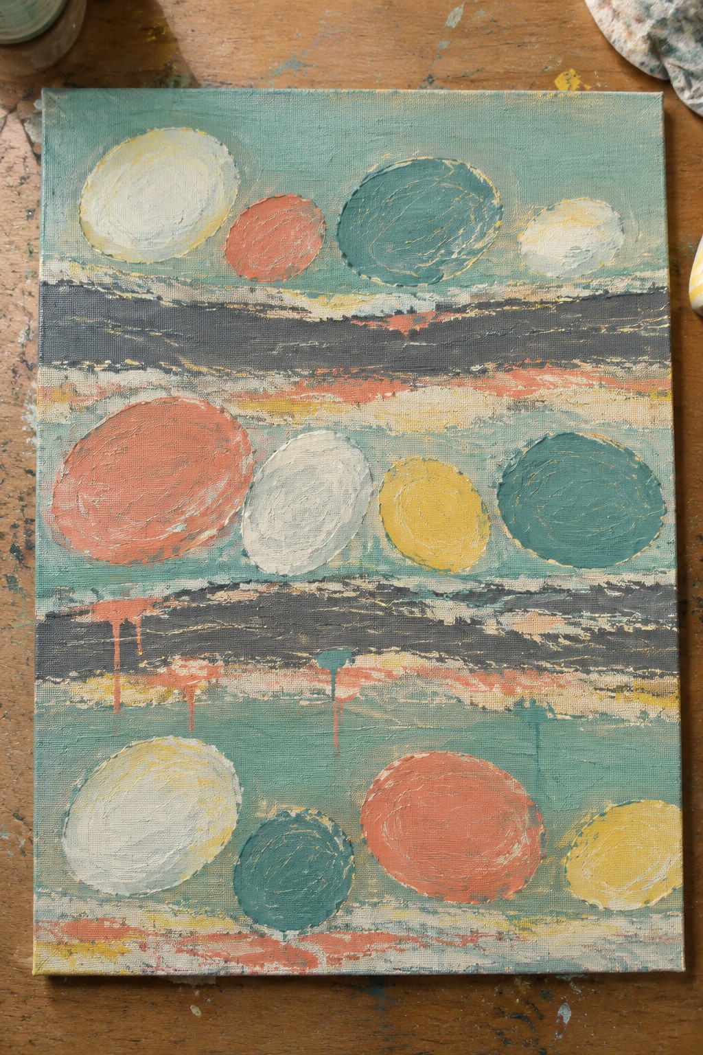 Abstract painting with colorful circles on textured teal and gray stripes