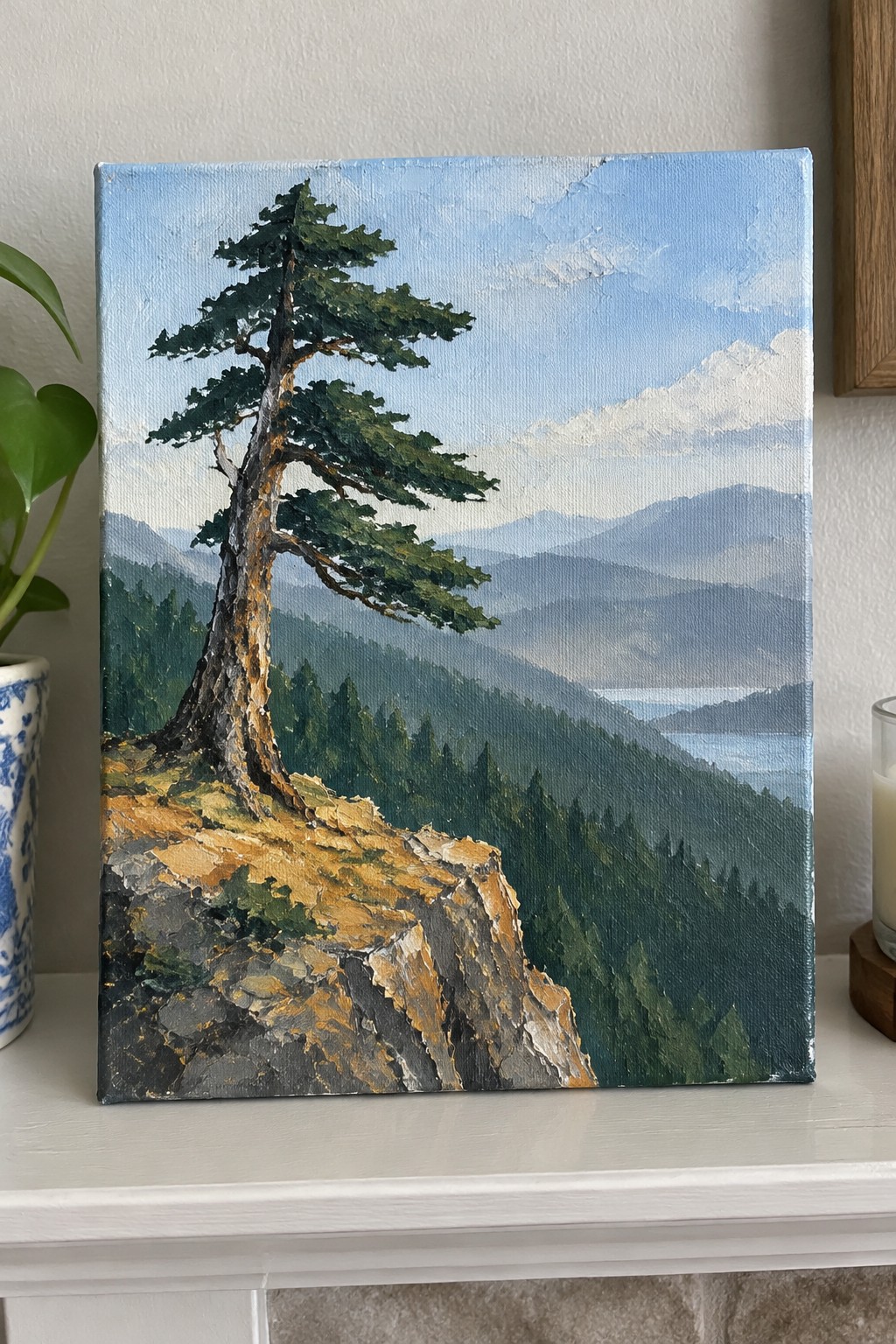 Painting of windswept pine tree on rocky cliff overlooking layered mountains and lake