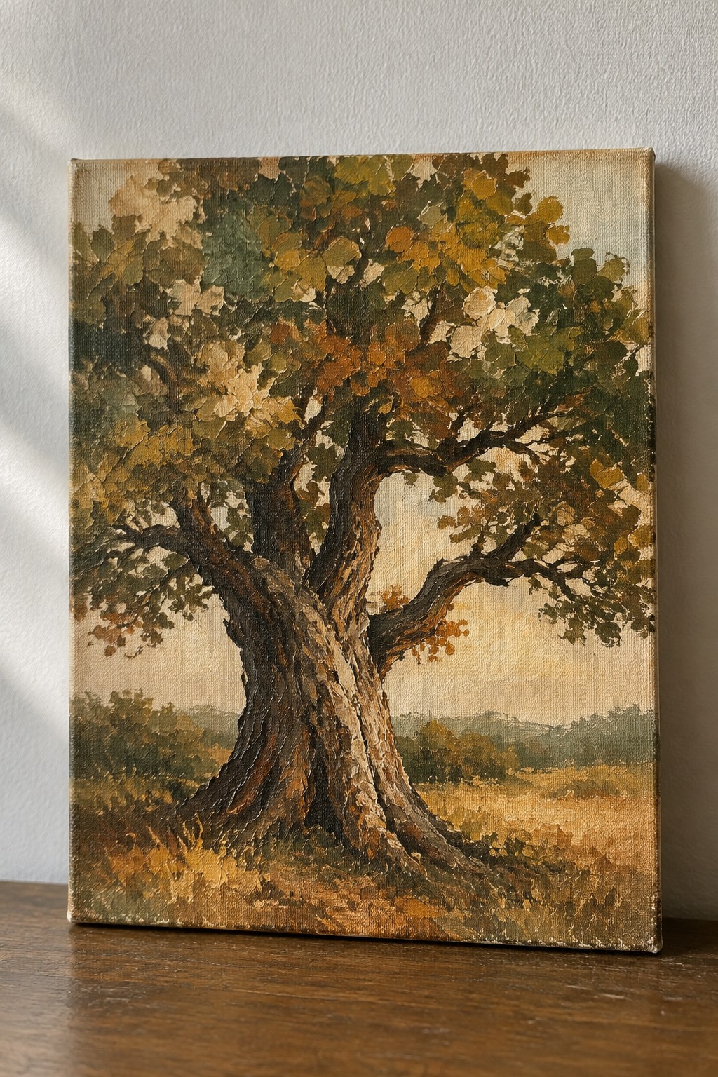 Large gnarled tree with green, yellow, and brown autumn foliage in landscape painting
