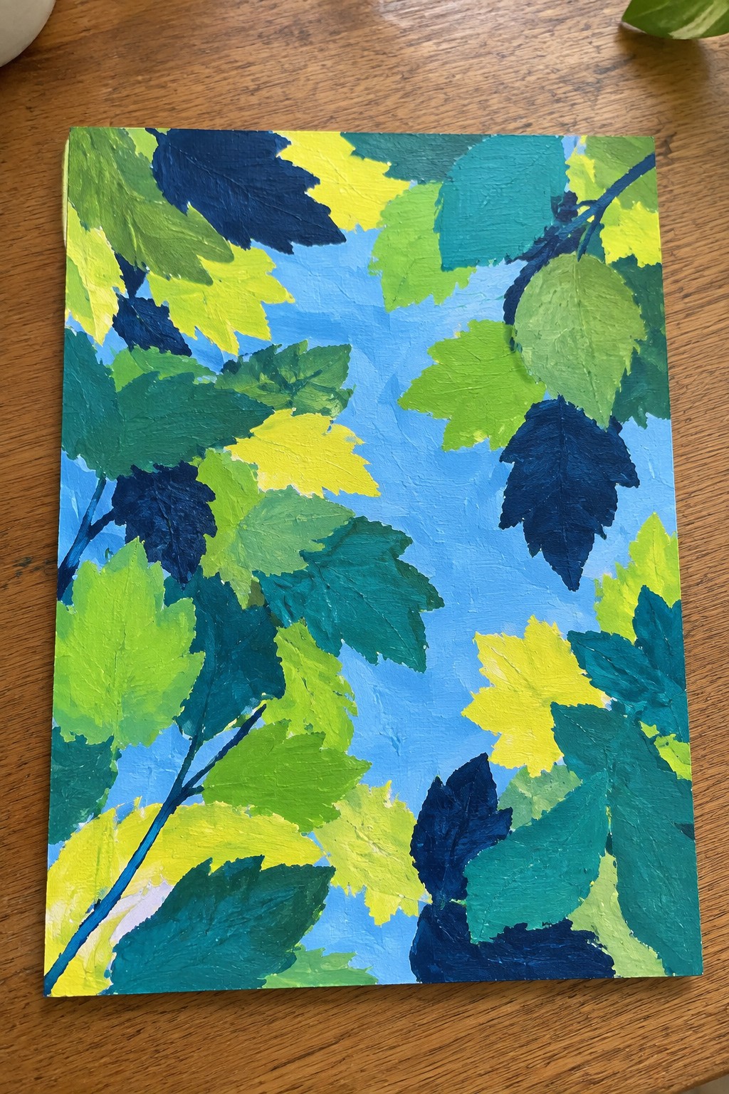 Vibrant impasto painting of overlapping leaves in greens, yellows, teal, and navy on blue
