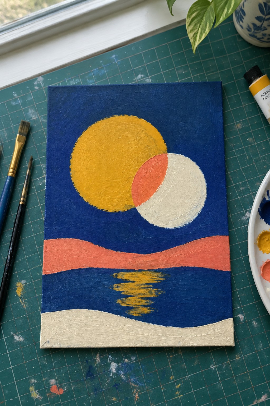 Abstract acrylic painting on canvas with yellow sun, overlapping circles, and wavy colorful bands amid supplies