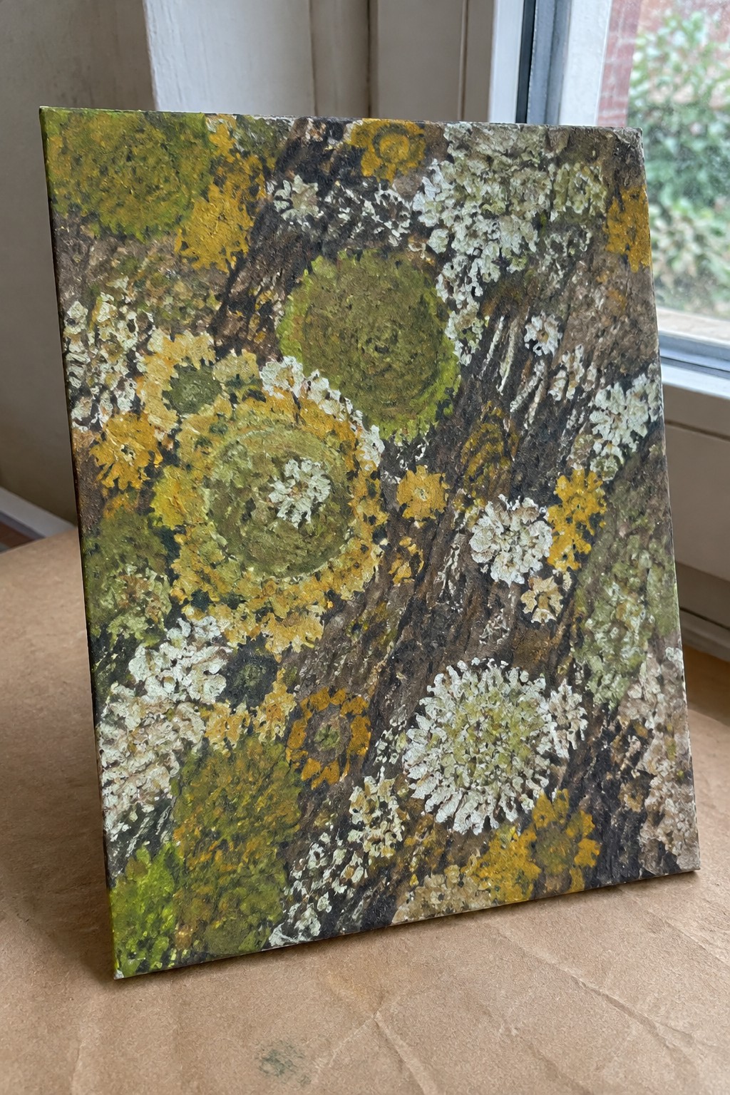 Vibrant painting of yellow, white, and green lichens on brown tree bark