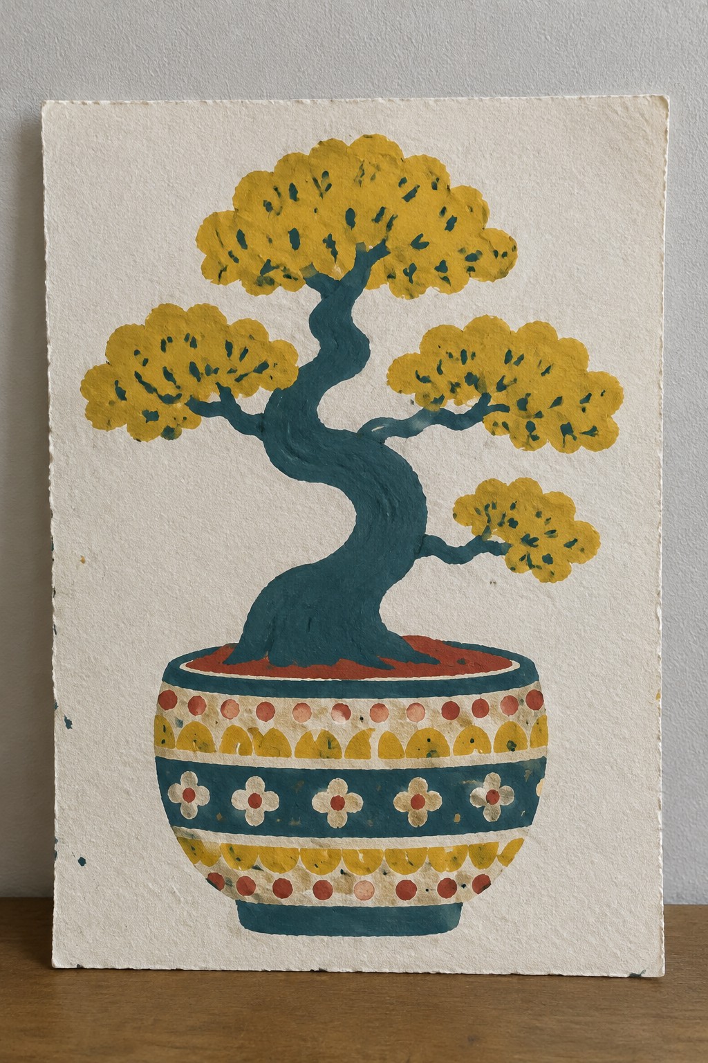 Curved teal-trunk bonsai with yellow foliage in an ornate patterned pot