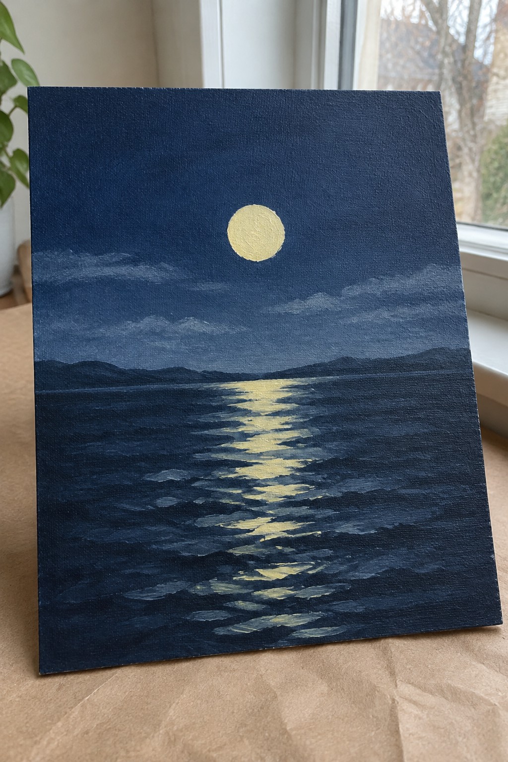 Canvas painting of yellow moon reflecting on dark blue rippled sea with distant hills.