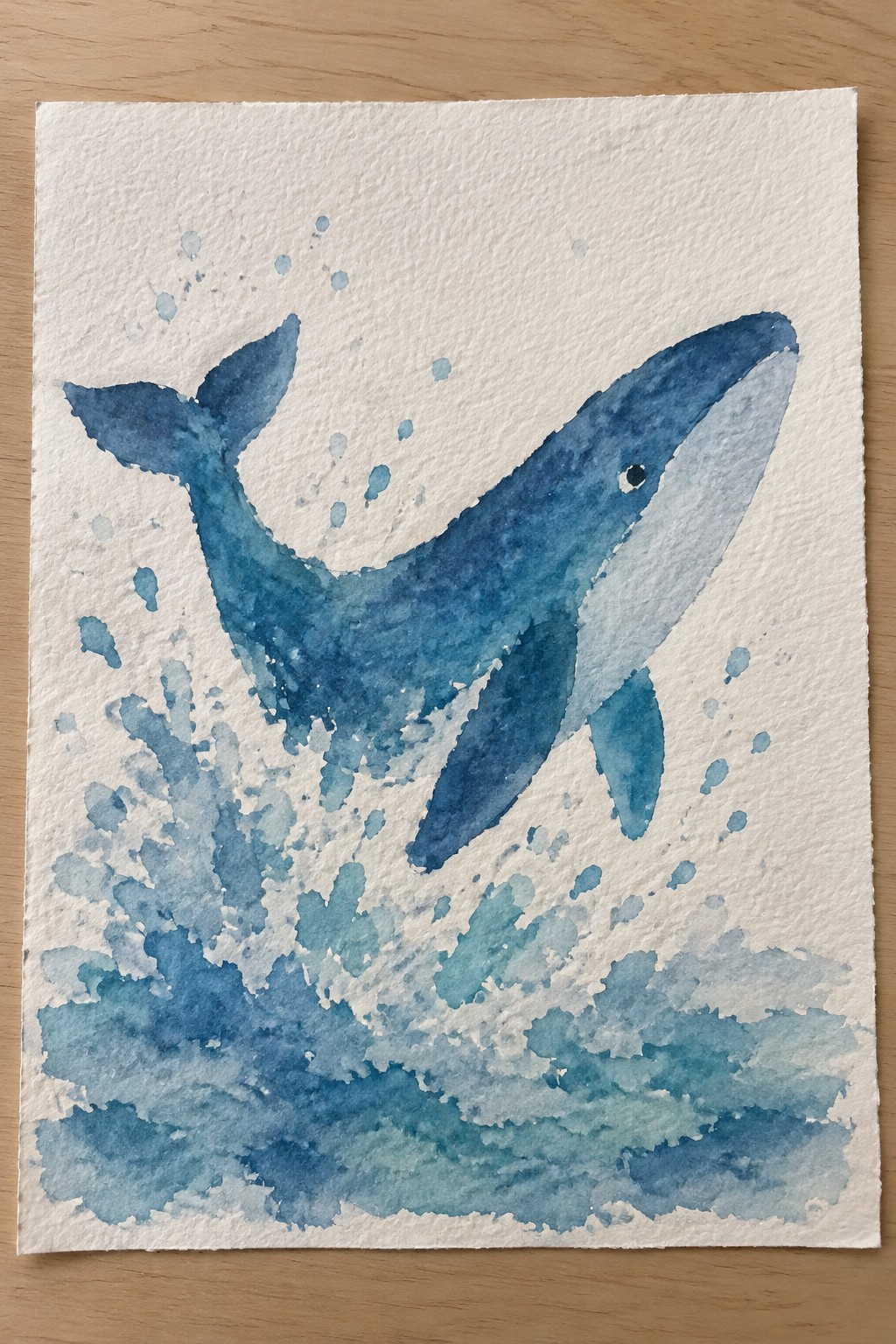 Blue watercolor whale breaching amid splashing waves, bubbles, and foam