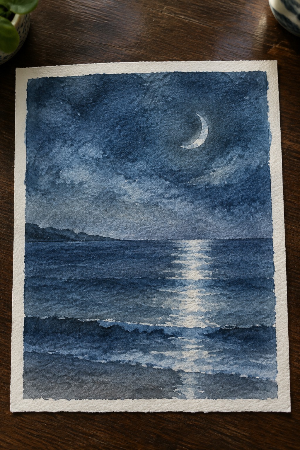 Watercolor night seascape with crescent moon and moonlight reflecting on dark blue waves