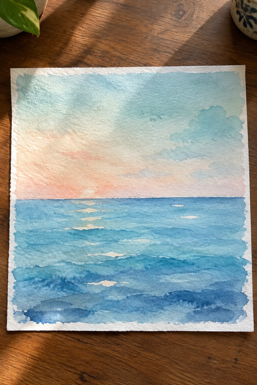 Watercolor seascape of blue ocean waves beneath pink and blue sunset sky on wood