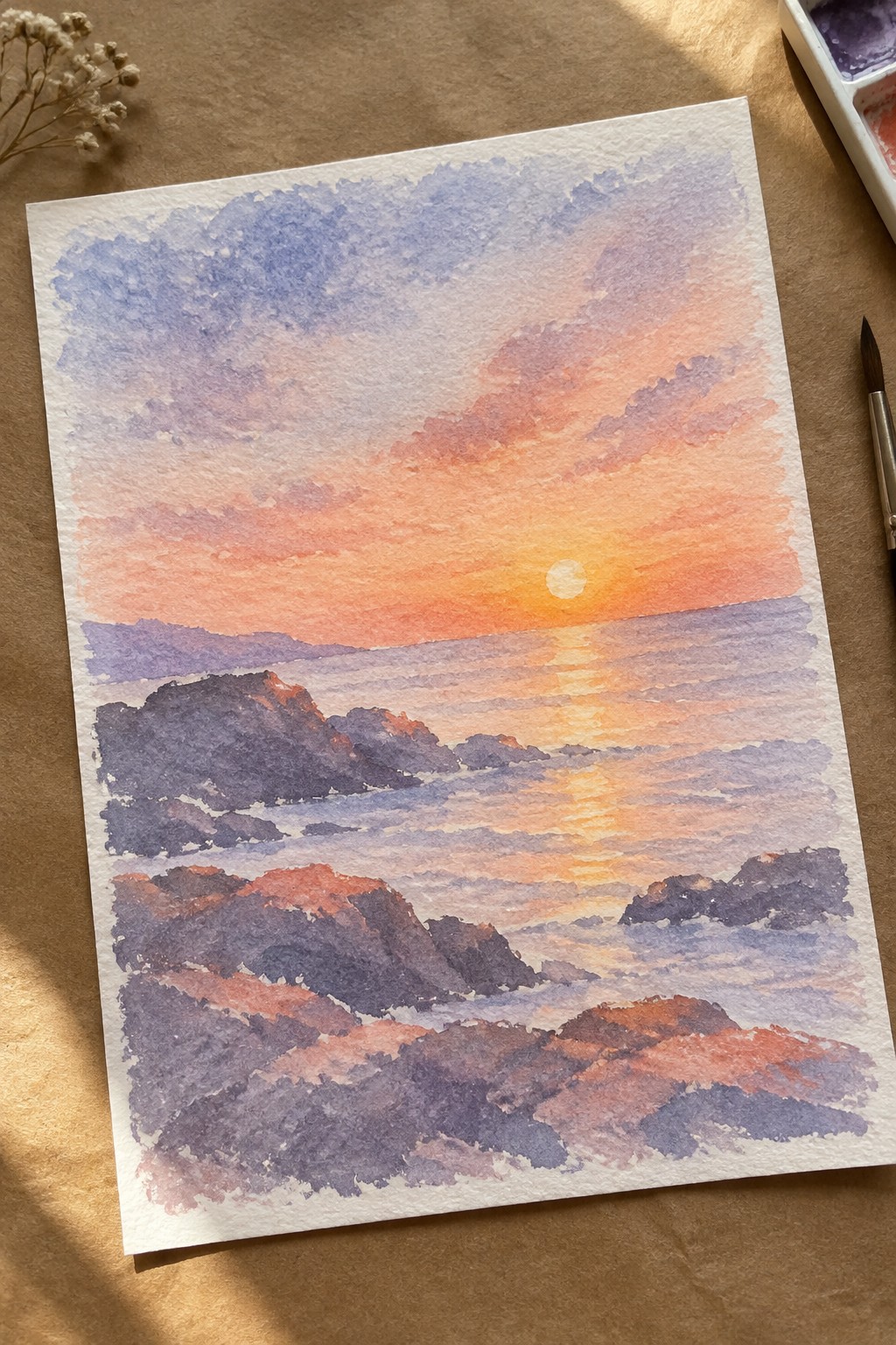 A watercolor painting of an ocean sunset with an orange-to-purple sky, a white sun on the horizon, and dark rocky islands in the water.