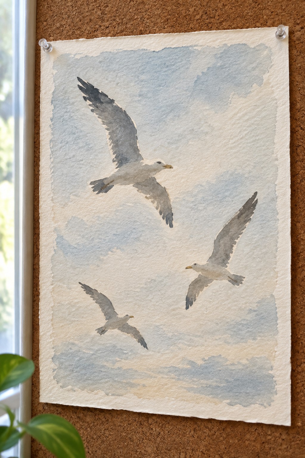 Three watercolor seagulls flying at different angles against a soft blue sky on textured paper.