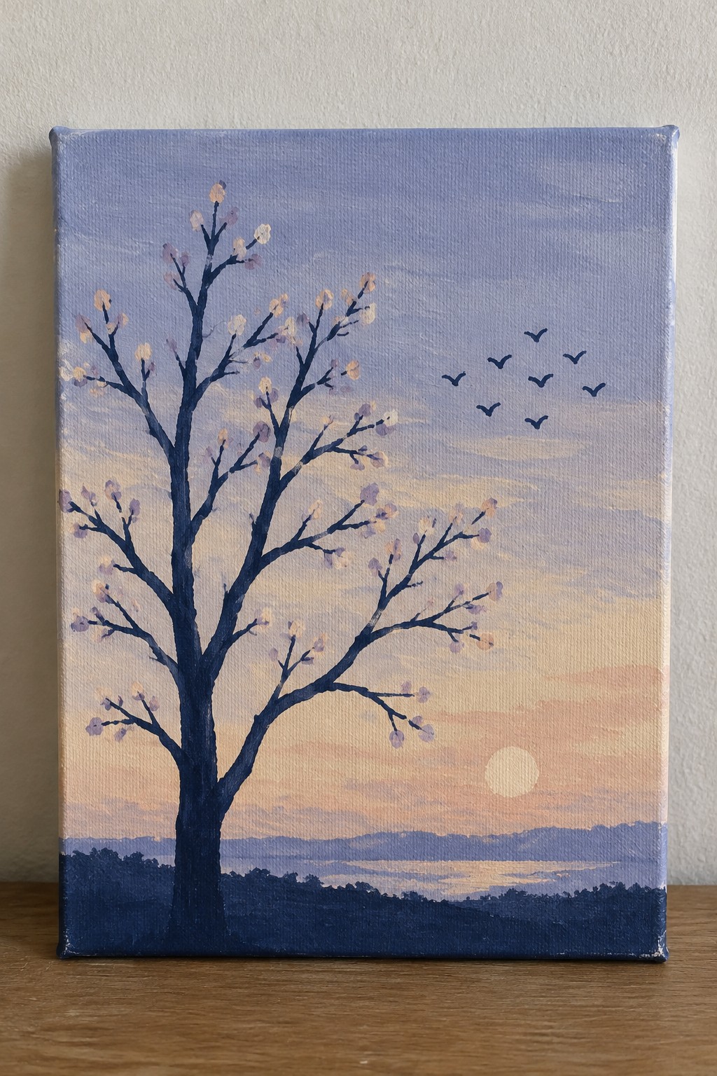 Silhouetted tree with blossoms beneath sunset sky with birds and rolling hills