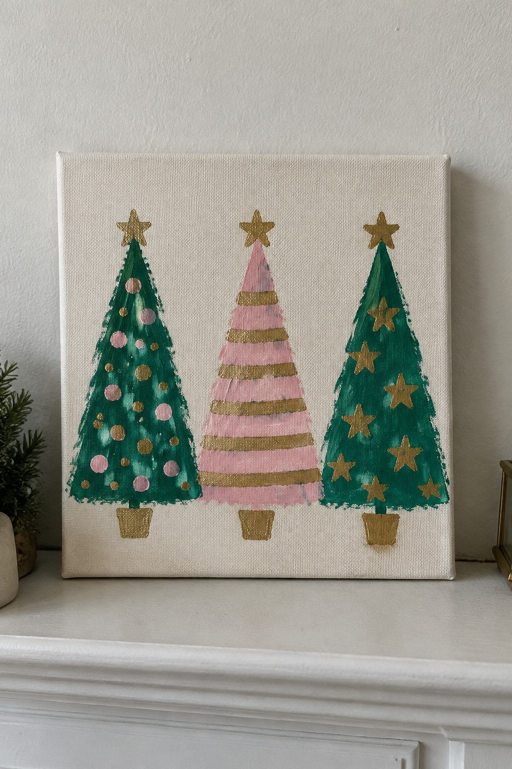 Three Christmas trees painted in green, pink, and gold on canvas