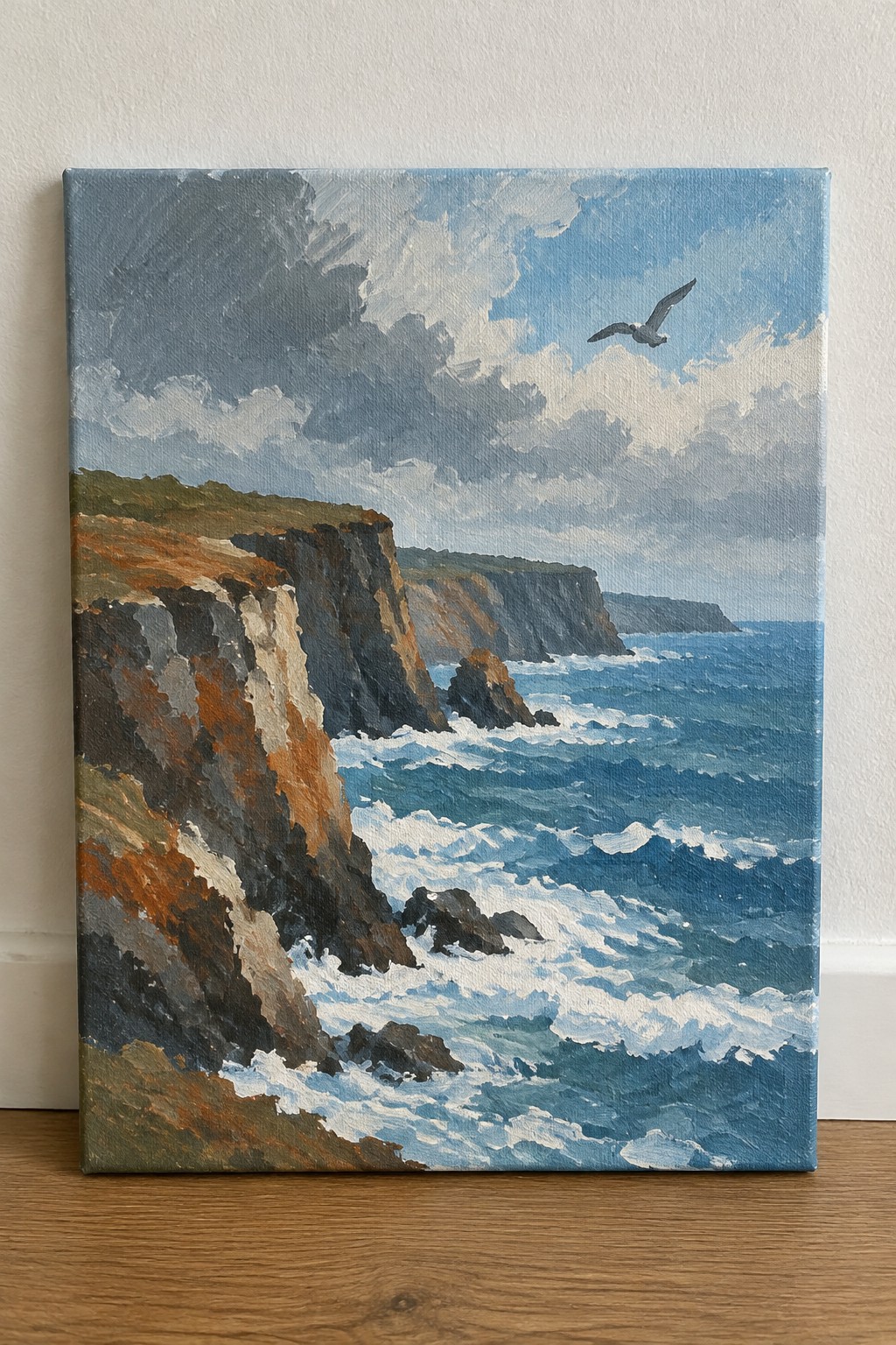 Oil painting of rugged sea cliffs, crashing blue waves, and flying seagull.