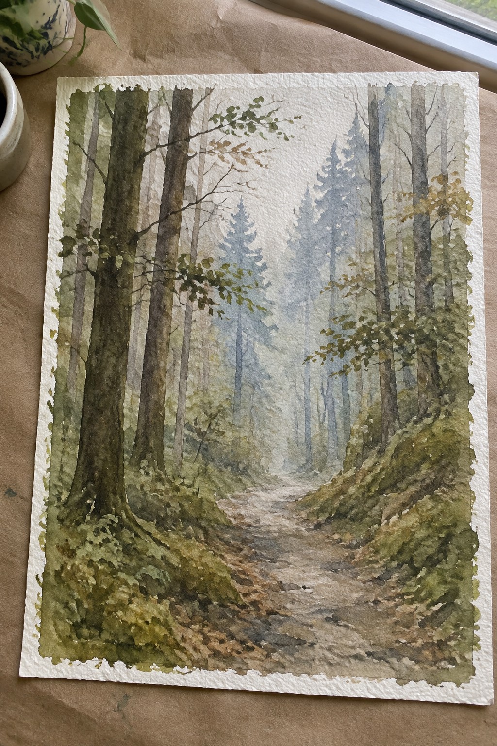 Watercolor painting of misty woodland path winding between tall trees and green slopes