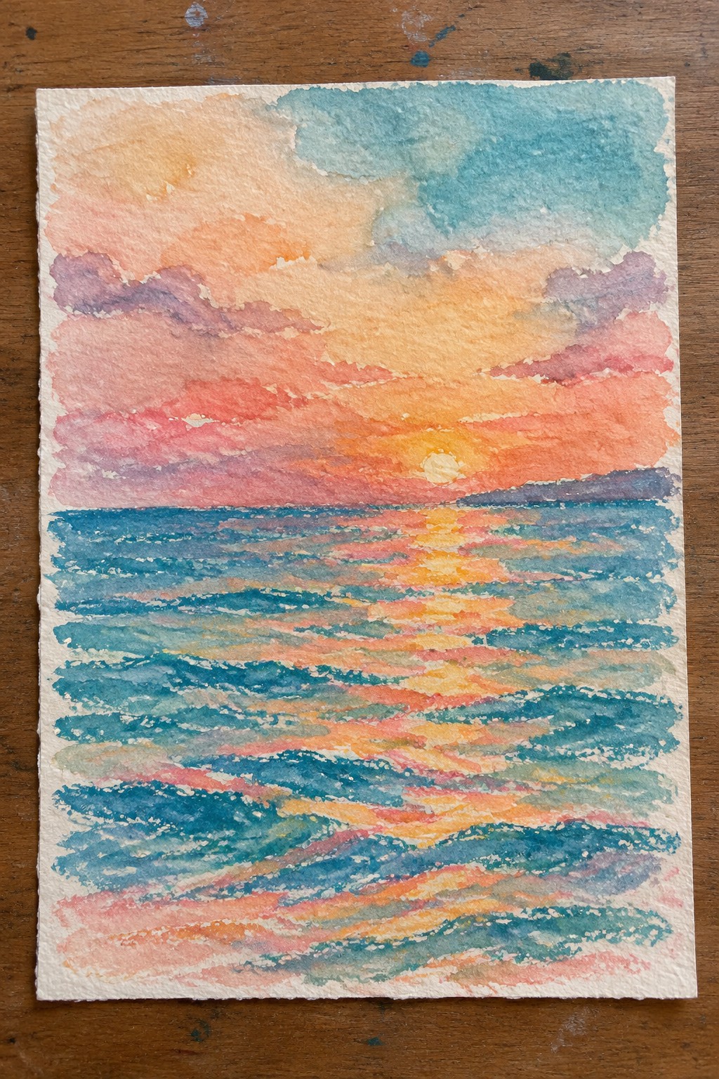 Watercolor painting of an ocean sunset with a low sun, colorful sky, and reflections across layered waves on paper.