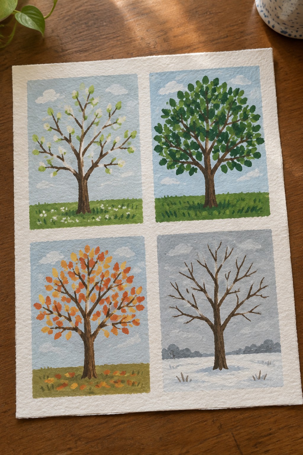 Watercolor painting of four trees in spring, summer, autumn, and winter.