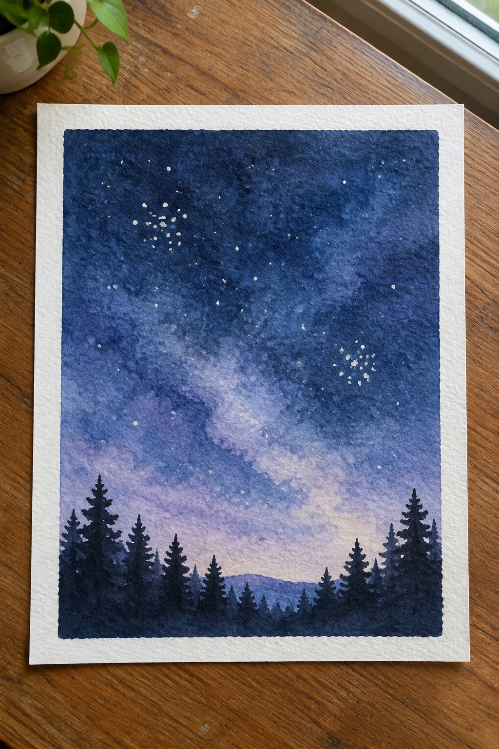 Watercolor of deep blue starry night sky above silhouetted pine forest on wood