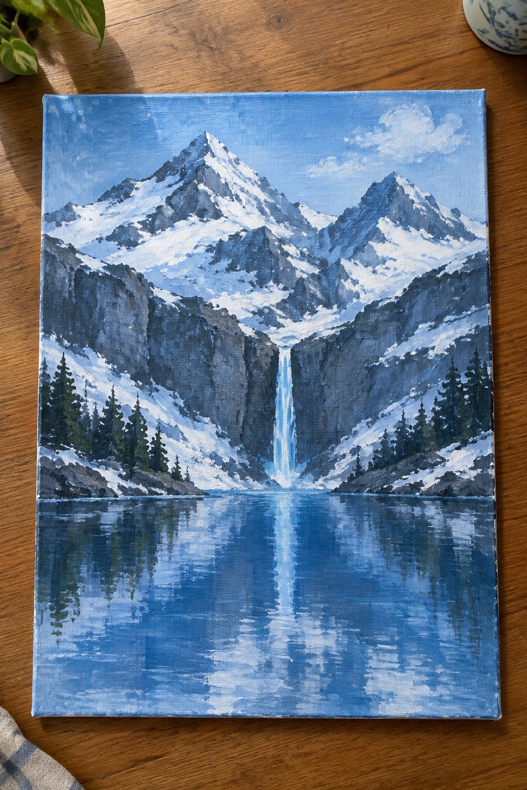 Oil painting of snow-capped mountains with waterfall reflecting in blue alpine lake
