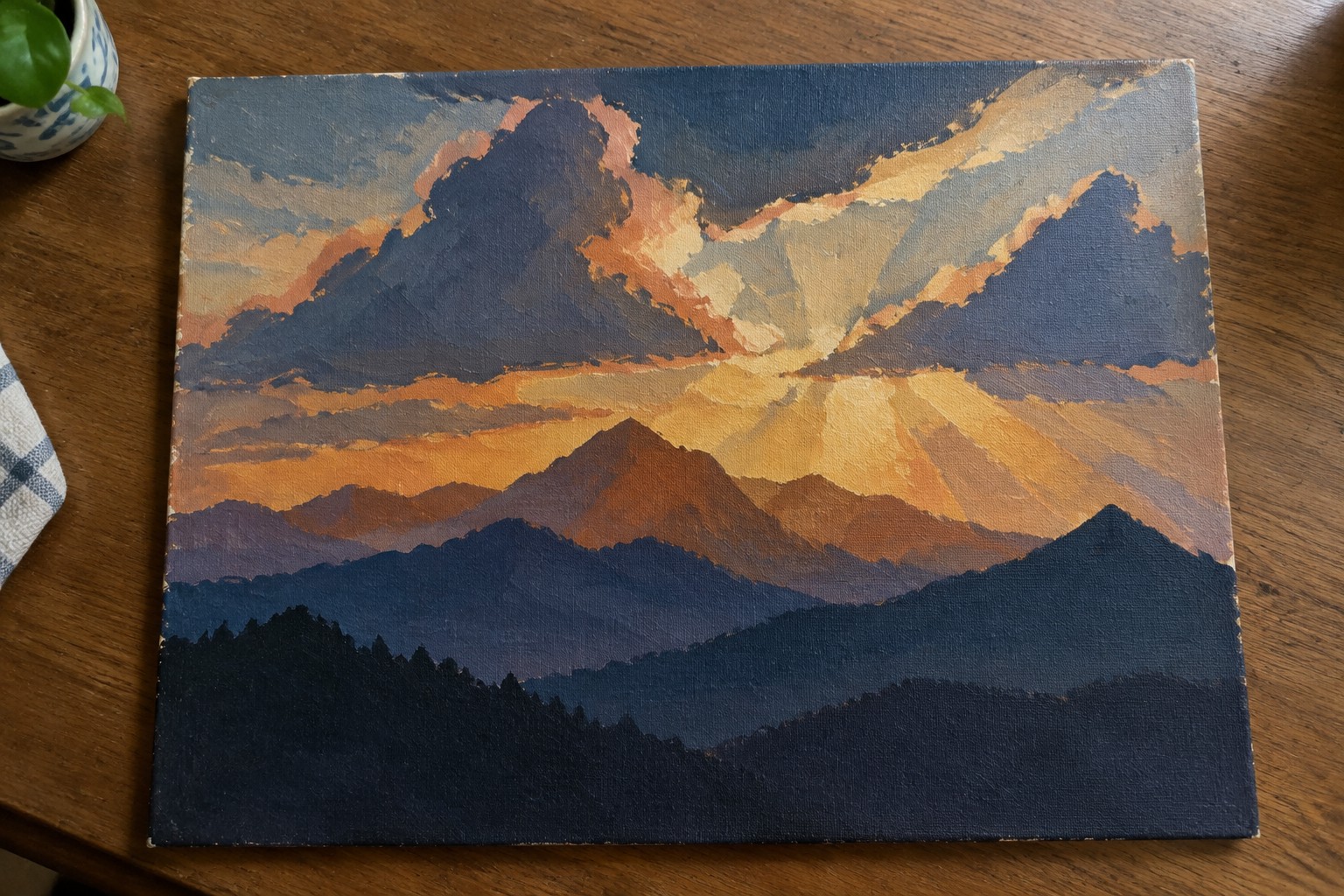 Stylized canvas painting of layered mountains at sunset with glowing orange sun rays
