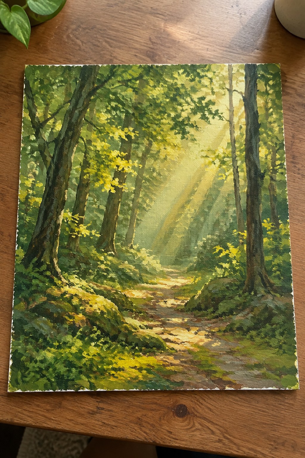 Sunlit forest path winding among tall green trees with golden light rays on wood table